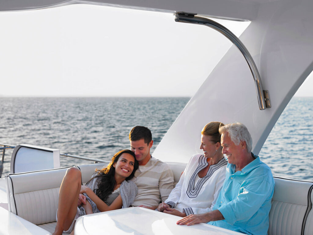 Happy young and middle aged couples relaxing on yacht